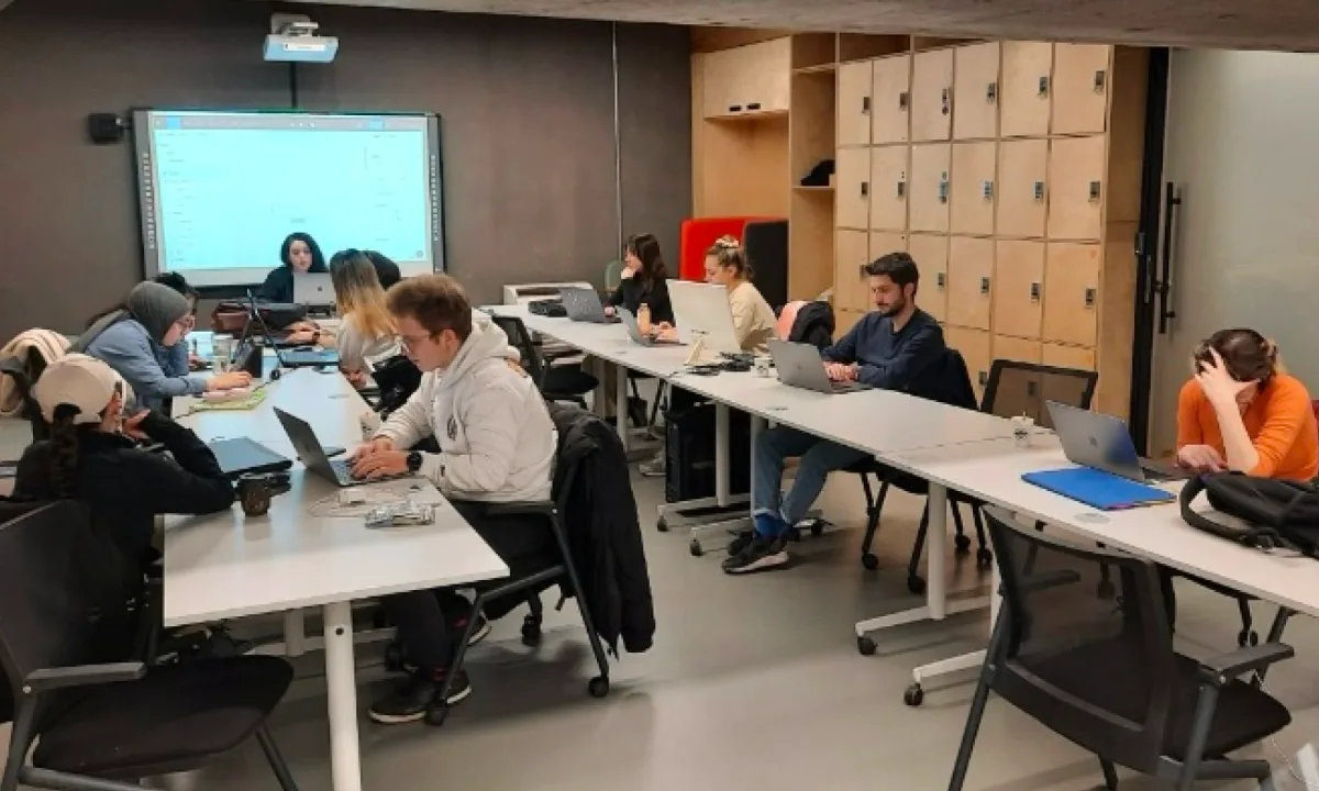 A class working on laptops at long tables