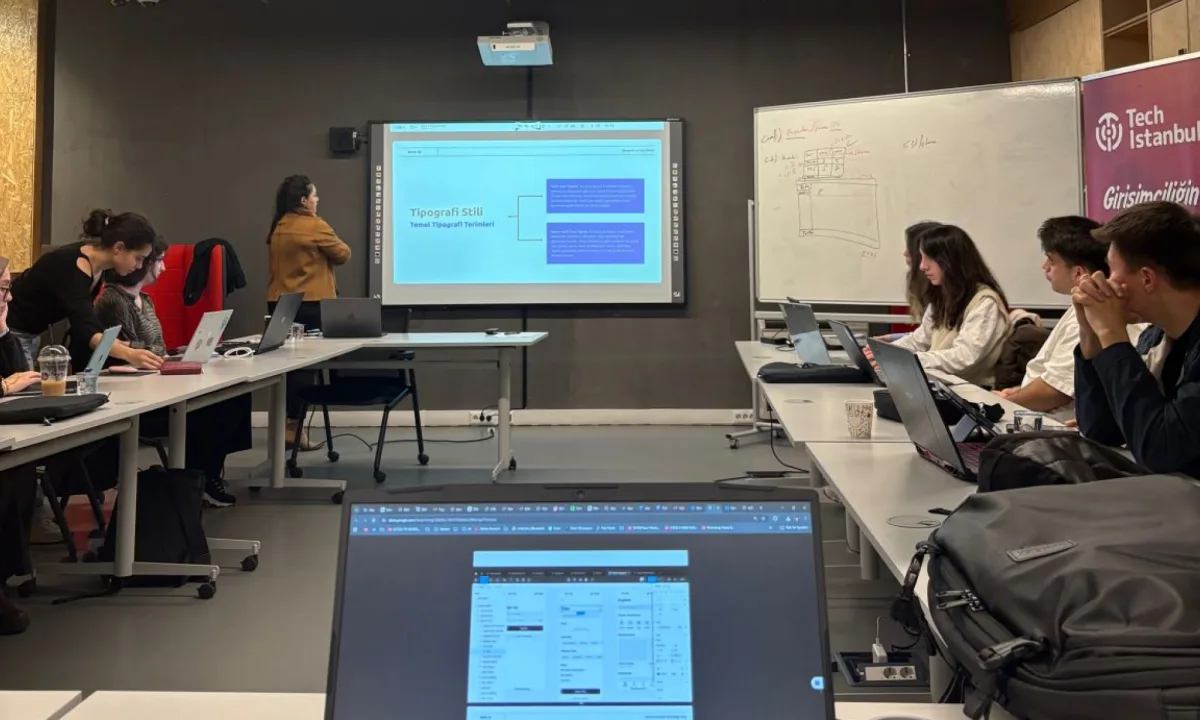 A trainer presenting a typography slide to a class working on laptops