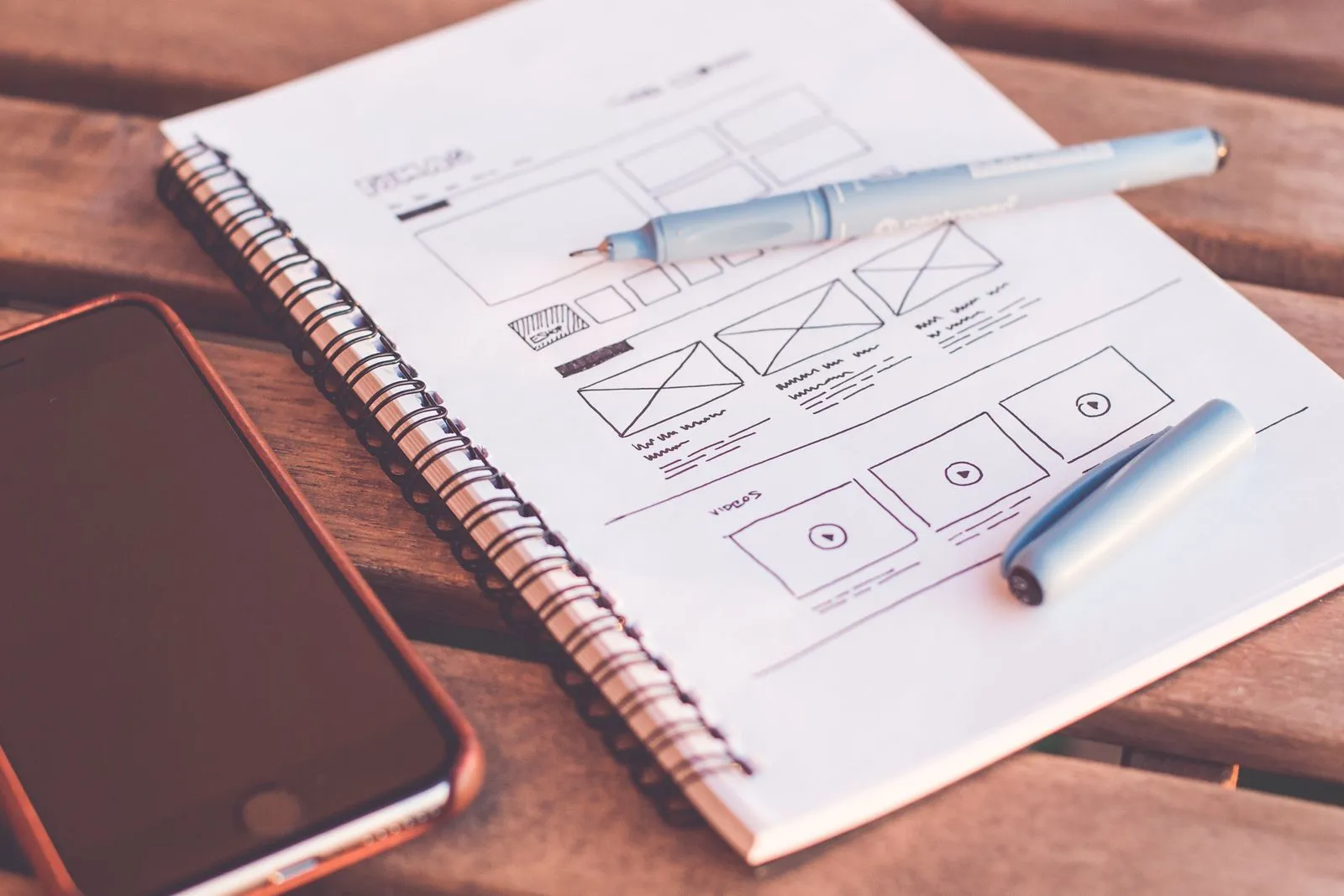 Wireframe sketches for an app in a notebook beside a phone